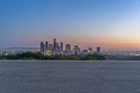 an open area with some benches in front of a large city skyline and blue sky