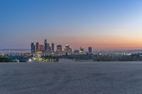 an open area with some benches in front of a large city skyline and blue sky