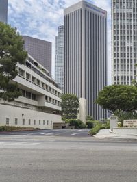 a street that has a road going into a building with several trees in the middle