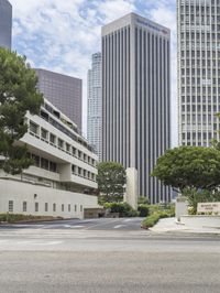 a street that has a road going into a building with several trees in the middle