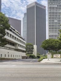 a street that has a road going into a building with several trees in the middle