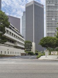 a street that has a road going into a building with several trees in the middle