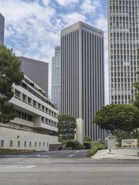 a street that has a road going into a building with several trees in the middle