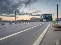 a roadway with concrete spheres along it on the side of the street under a cloudy sky