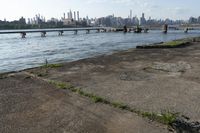 a bridge over a lake that's very wide with city buildings and water in the background