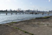 a bridge over a lake that's very wide with city buildings and water in the background