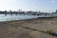 a bridge over a lake that's very wide with city buildings and water in the background