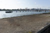 a bridge over a lake that's very wide with city buildings and water in the background