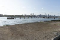 a bridge over a lake that's very wide with city buildings and water in the background