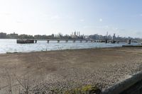 a bridge over a lake that's very wide with city buildings and water in the background