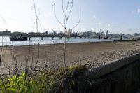 a bridge over a lake that's very wide with city buildings and water in the background