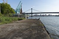 the walkway extends over to a bridge near the river with buildings in the background and water on either side