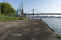 the walkway extends over to a bridge near the river with buildings in the background and water on either side