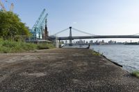 the walkway extends over to a bridge near the river with buildings in the background and water on either side