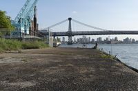 the walkway extends over to a bridge near the river with buildings in the background and water on either side