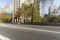 there is a street with trees and buildings on it and a red bus going by