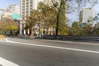 there is a street with trees and buildings on it and a red bus going by
