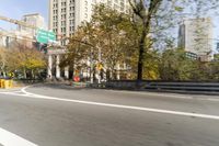 there is a street with trees and buildings on it and a red bus going by