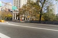 there is a street with trees and buildings on it and a red bus going by