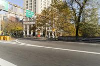 there is a street with trees and buildings on it and a red bus going by