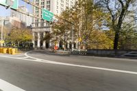 there is a street with trees and buildings on it and a red bus going by
