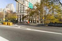 there is a street with trees and buildings on it and a red bus going by