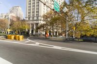 there is a street with trees and buildings on it and a red bus going by