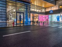 people walk outside a shopping mall that has been converted into a building in the evening