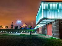 a night time photo with the building lit up and the green grass growing out of the ground