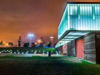 a night time photo with the building lit up and the green grass growing out of the ground