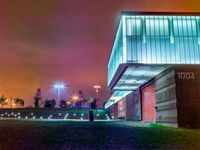 a night time photo with the building lit up and the green grass growing out of the ground