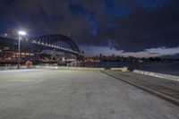 a city with lots of buildings and a river and a bridge at night in the background