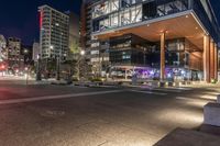 a city street with tall buildings and light up lights at night time outside the building