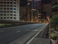 the city street is empty of traffic as it crosses over a bridge at night time