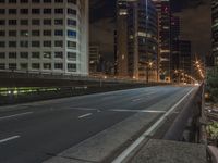 the city street is empty of traffic as it crosses over a bridge at night time