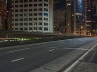 the city street is empty of traffic as it crosses over a bridge at night time