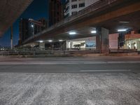 a highway going under an overpass in downtown at night time, with traffic lights