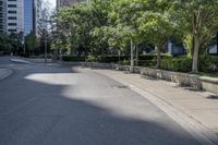 a car driving down an empty street lined with tall buildings and trees in the background