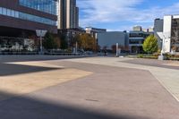 an empty courtyard in front of many buildings and trees in the middle of town, with a bench on a sidewalk