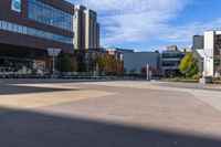 an empty courtyard in front of many buildings and trees in the middle of town, with a bench on a sidewalk