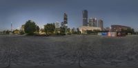 a wide angle panoramic view of a city from an empty park area with trees