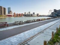 many benches line the edge of a bridge overlooking a city river and a body of water