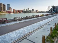 many benches line the edge of a bridge overlooking a city river and a body of water