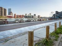 many benches line the edge of a bridge overlooking a city river and a body of water