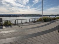 the view of the river and the sidewalk with a skateboarder on it in a city