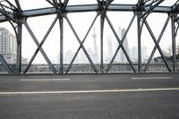 a street next to a bridge with skyscrapers in the background and yellow line on it