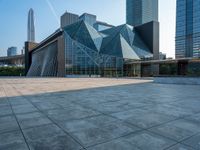 an empty courtyard and building with an entrance leading to it and tall buildings behind it