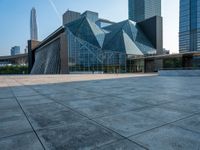 an empty courtyard and building with an entrance leading to it and tall buildings behind it