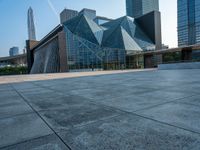 an empty courtyard and building with an entrance leading to it and tall buildings behind it