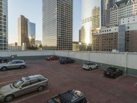 a parking lot with cars parked in it near tall buildings and another building in the background